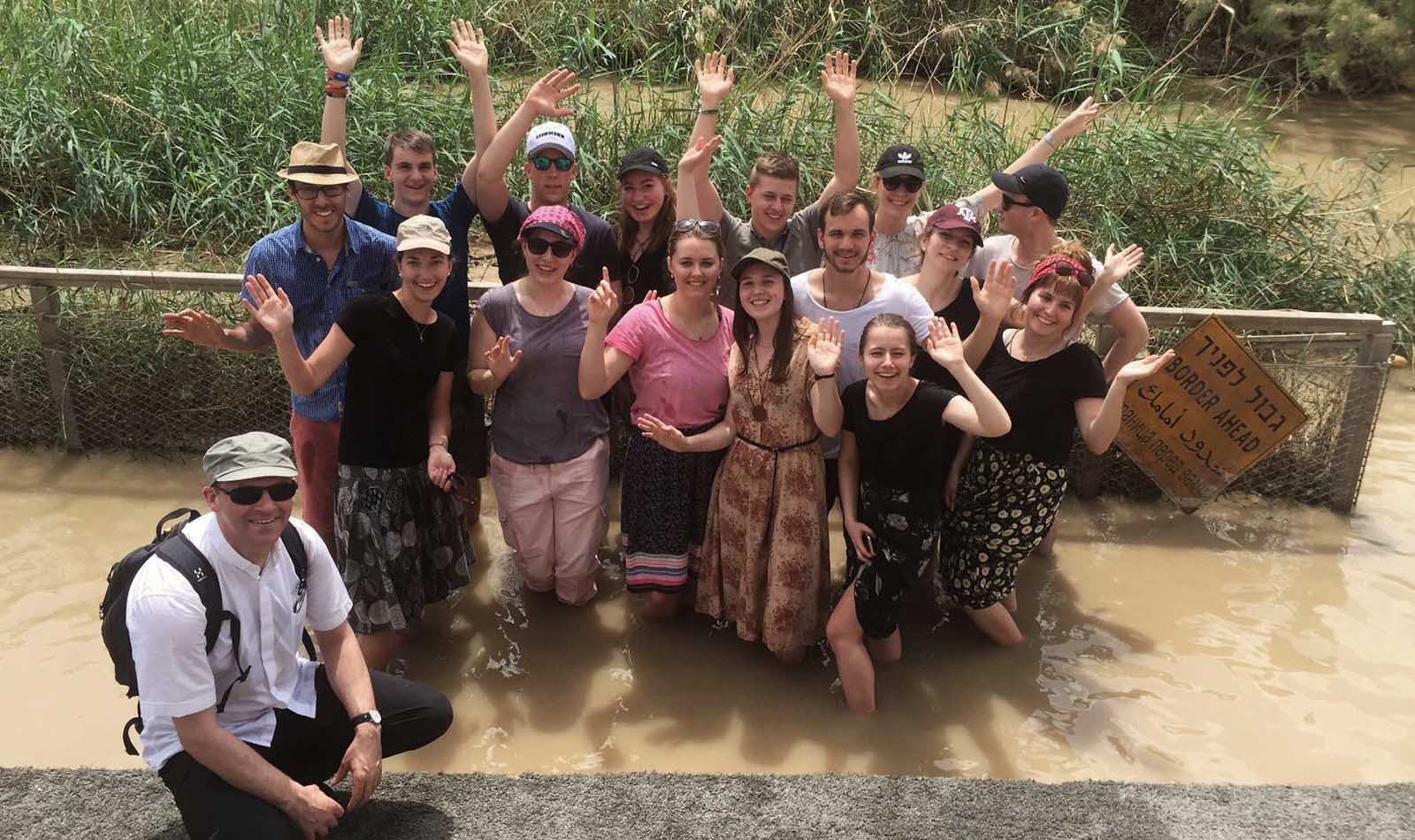 Gruppe junger Menschen, die bis zu den Knien in einem Fluss stehen