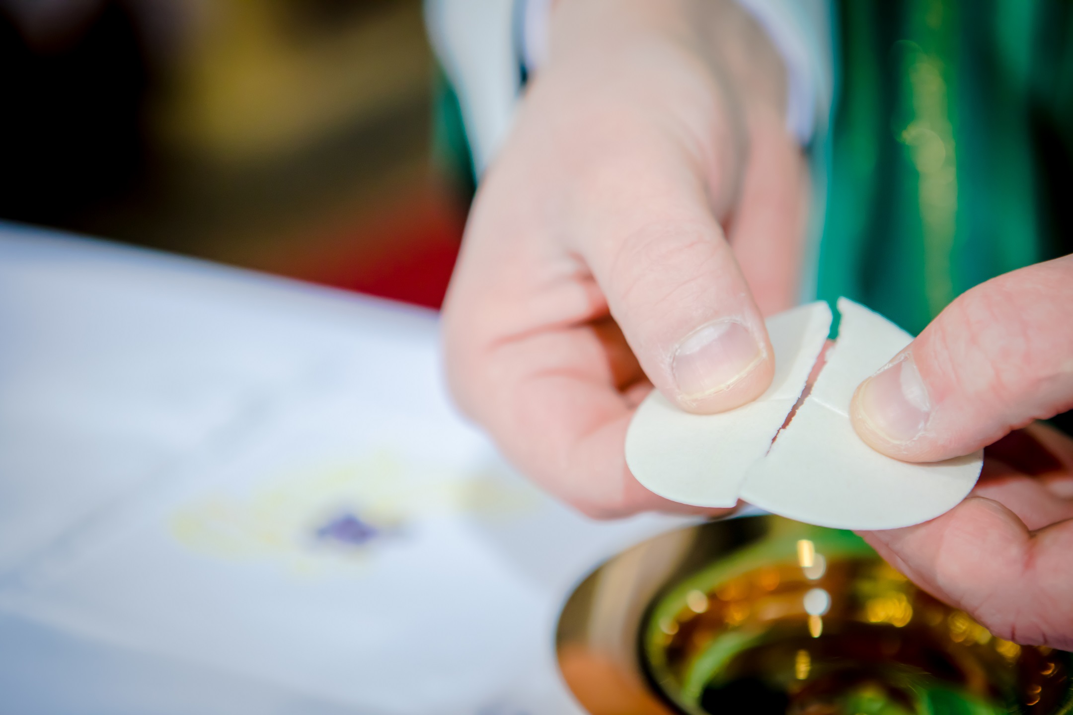 Priester bricht Brot bei Eucharistie