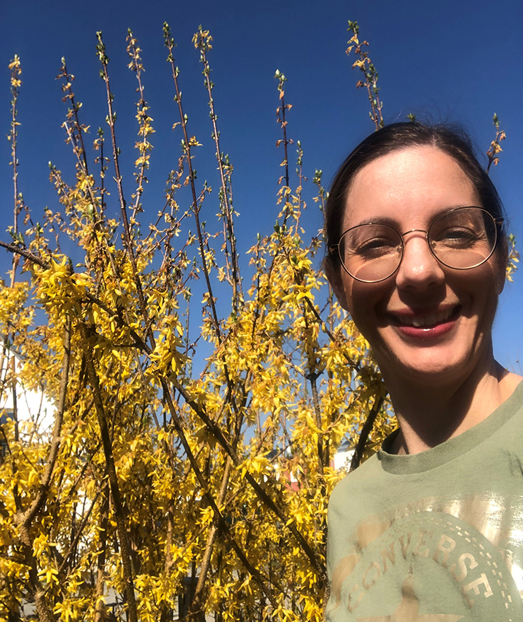 Junge Frau mit Brille vor gelber Forsythie