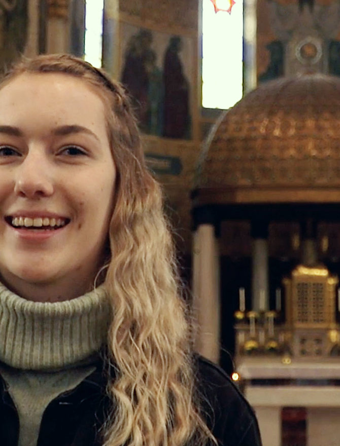 Junge Frau mit langen blonden lockigen Haaren vor dem Altar der Herz-Jesu-Kirche in Augsburg.