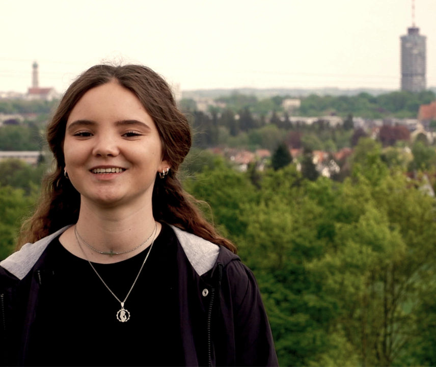 Junge Frau in schwarrzer Kleidung vor Augsburg-Panorama