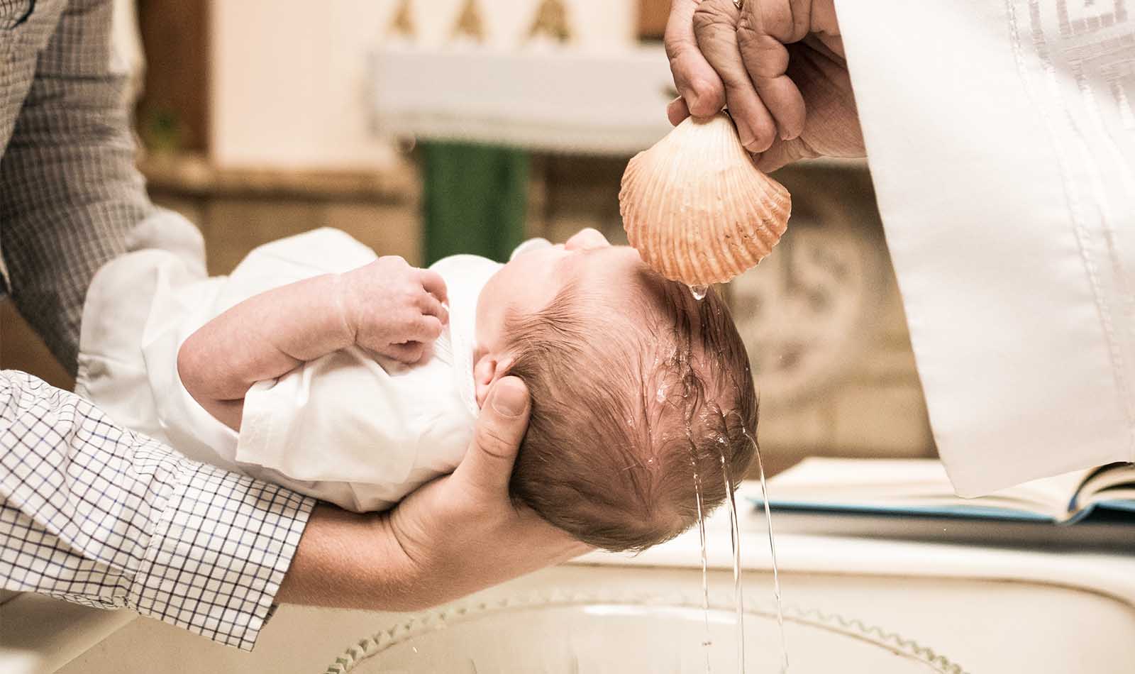 Baby wird bei der Taufe mit Wasser übergossen