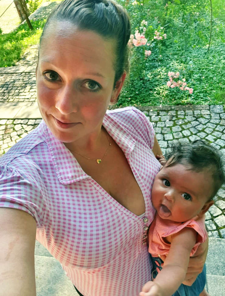 Junge Frau in Trachtbluse mit Baby im Arm