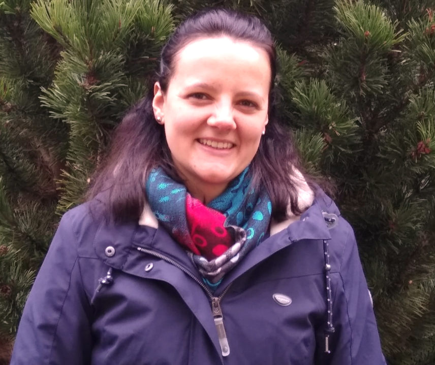 Junge europäische Frau mit braunen Haaren und buntem Schal in lila Windjacke
