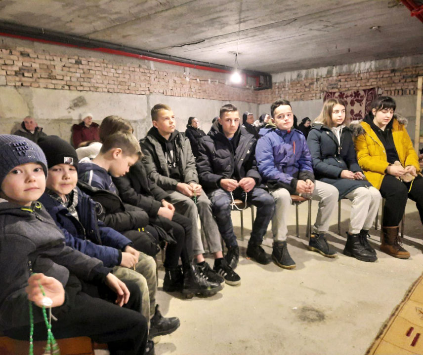 Ukrainische Kinder und Jugendliche beim Rosenkranzgebet im Keller