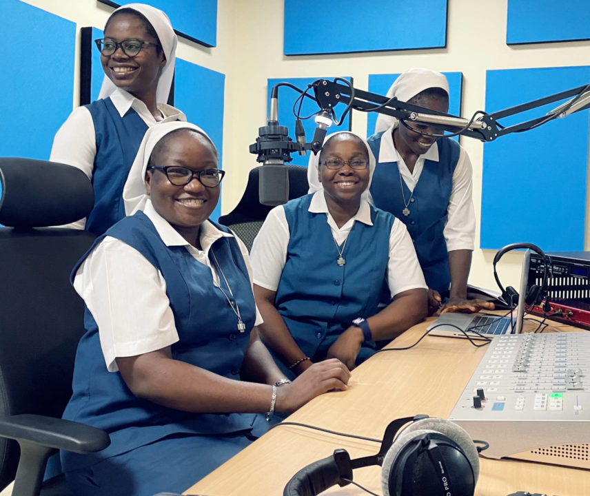 Vier Ordensschwestern hinter einem Radio-Mikrophon