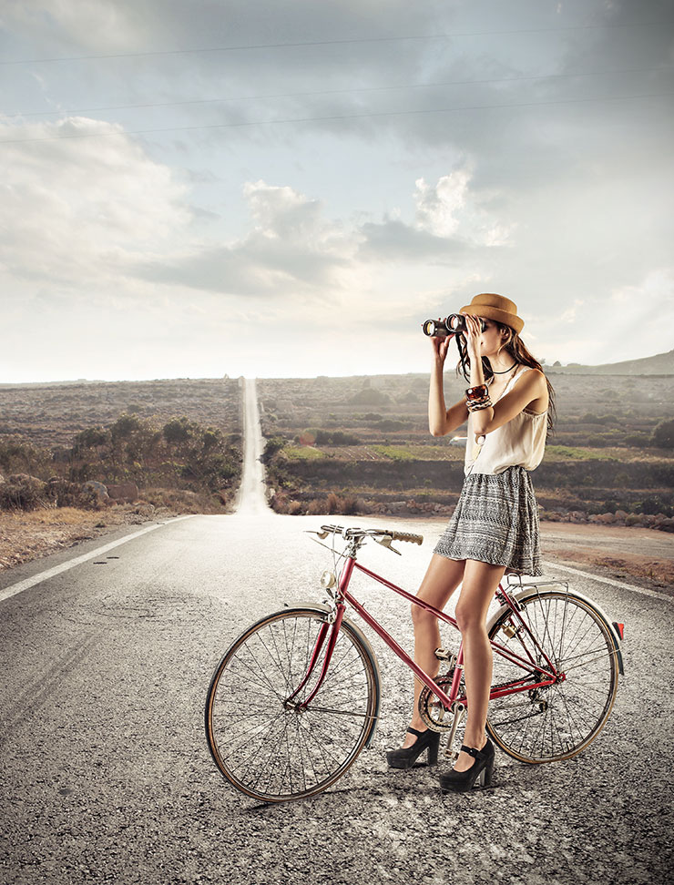 Junge Frau auf Fahrrad in Steppe mit Fernglas.