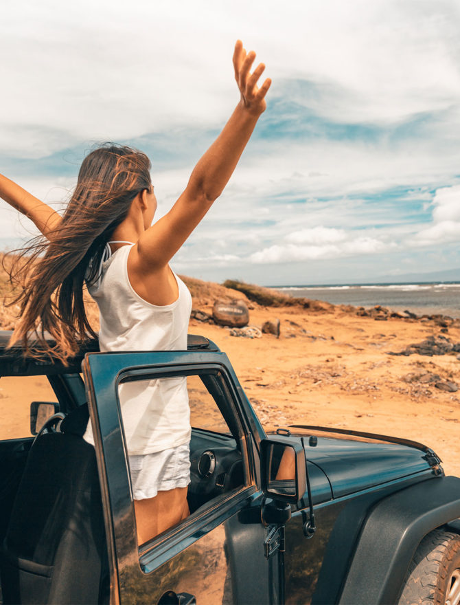 Junge Frau mit guter Laune in Jeep am Strand.