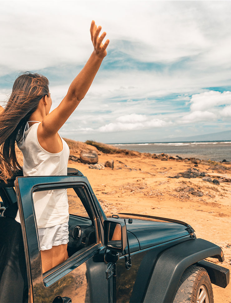 Junge Frau mit guter Laune in Jeep am Strand.