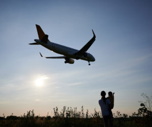 Menschen beobachten ein landendes Flugzeug am Abend.