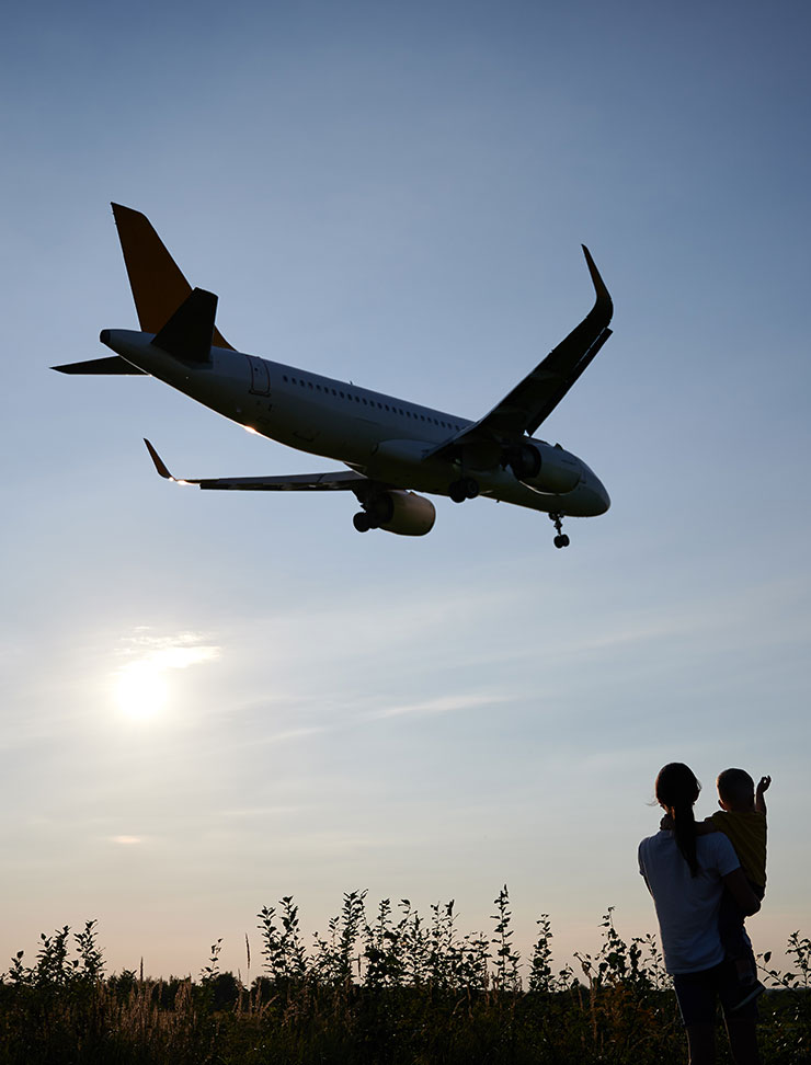 Menschen beobachten ein landendes Flugzeug am Abend.