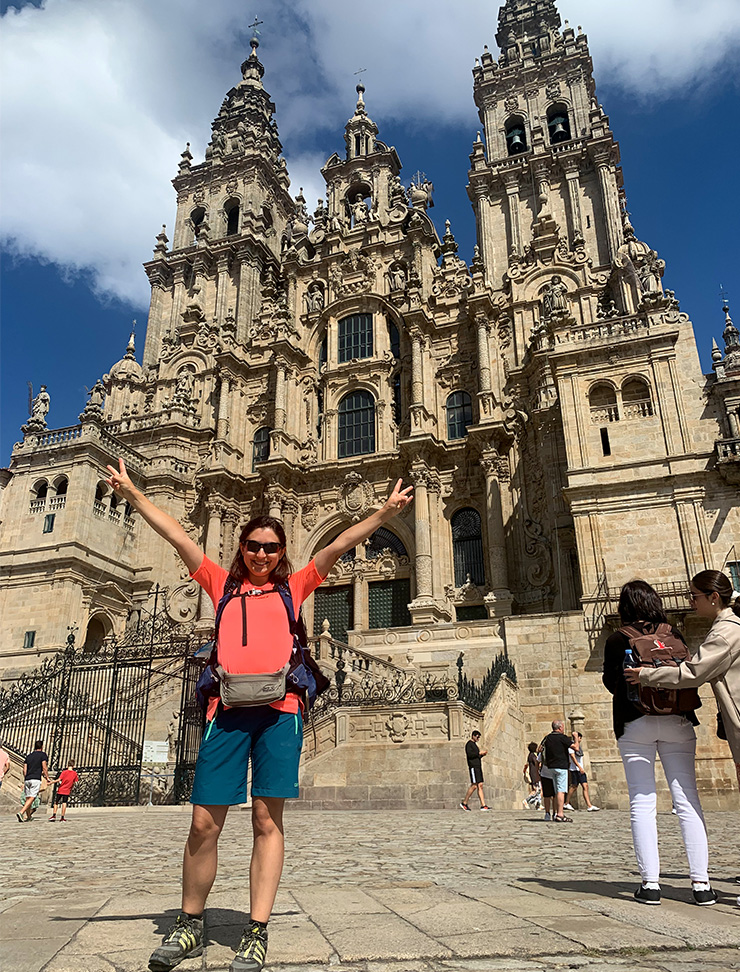 Junge dunkelhaarige Frau mit orangem T-Shirt jubelnd in Santiago de Compostela