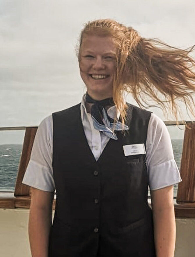 Junge Frau an Bord eines Schiffes mit Haaren im Wind.