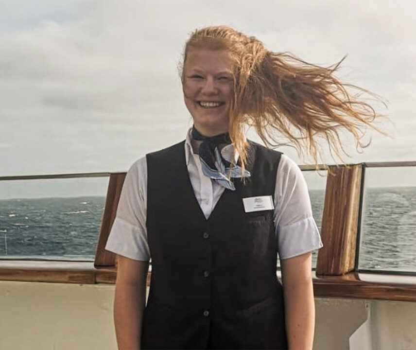Junge Frau an Bord eines Schiffes mit Haaren im Wind.