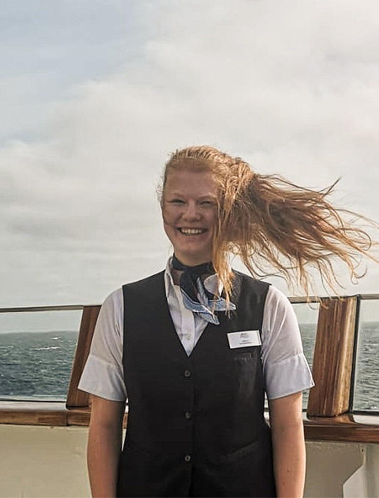 Junge Frau an Bord eines Schiffes mit Haaren im Wind.