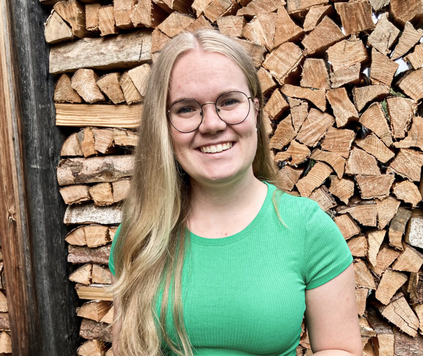 Junge Frau in grünem T-Shirt vor Holzhintergrund