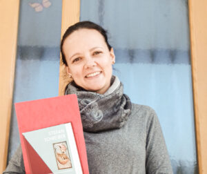 Junge europäische Frau mit schwarzen Haaren und Studienmaterial Theologie vor einem Fenster