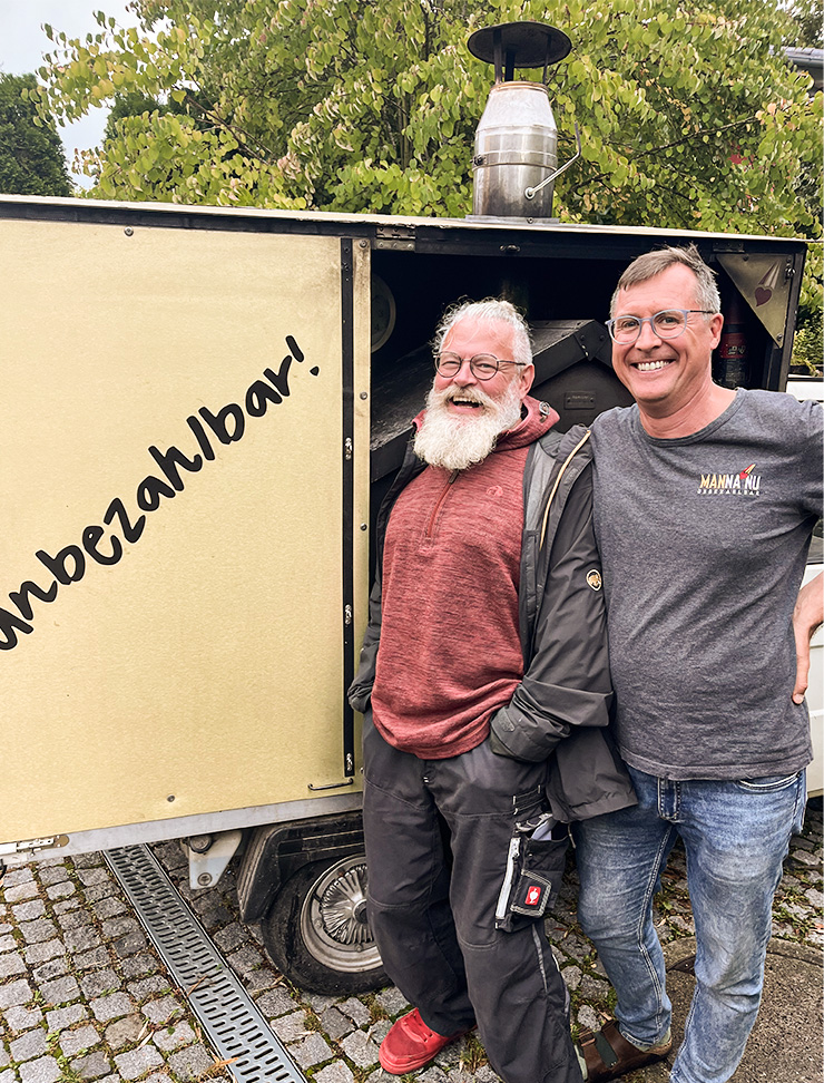 Mannanu-Mitarbeiter lachend vor ihrem Einsatzufahrzeug