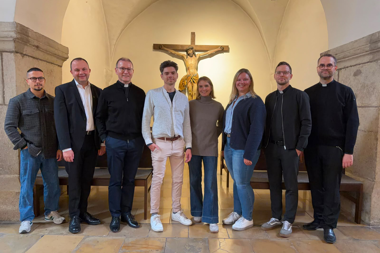 8 Personen mit Priestern vor einem Kruzifix mit Jesus Christus in der Kirche St. Peter am Perlach in Augsburg